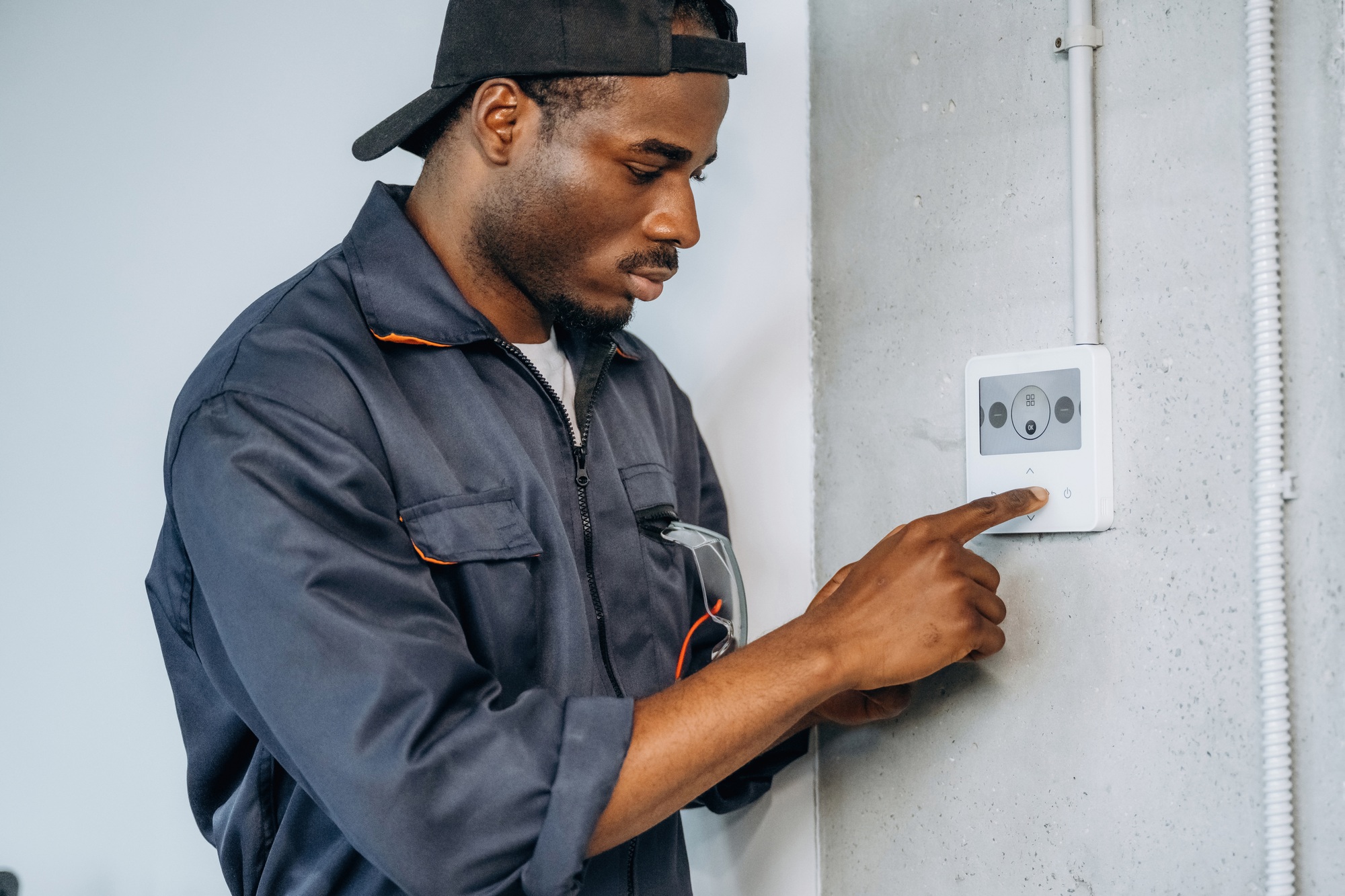 Examining the thermostat. Repairman is indoors in the modern office