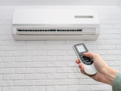 home air conditioner and man hand with remote control closeup home air conditioner and man hand with remote control closeup